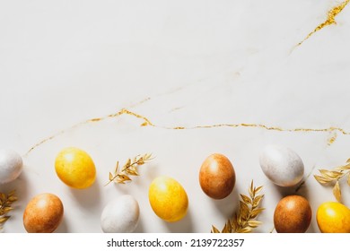 Luxury Easter eggs and golden branches on marble table. Happy Easter greeting card template. Easter frame border. Flat lay, top view, copy space.