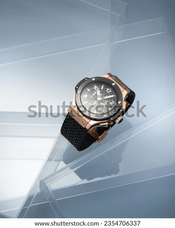 Luxury elegant gold men's watch with a dark dial and a black strap on a beautiful blue background with line elements, watch advertising for watch shops. With space for text or inscriptions

