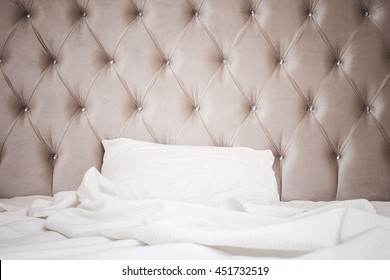 Luxury empty bedroom interior fragment, soft pink headboard, white bedding sheet and pillow lay on wide empty bed - Powered by Shutterstock