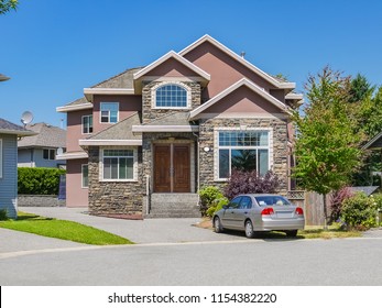 Luxury Family House With A Car Parked On Concrete Driveway. Residential House On Sunny Day On Blue Sky Background