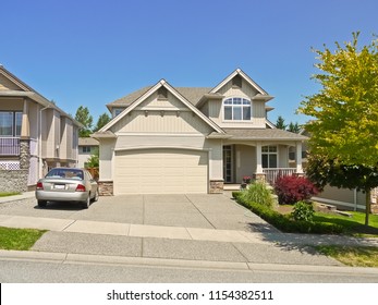 Luxury Family House With A Car Parked On Concrete Driveway. Residential House On Sunny Day On Blue Sky Background