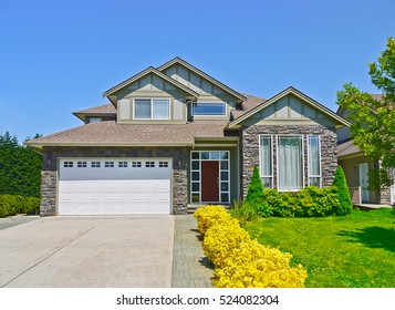 Luxury Family House With Concrete Driveway To The Garage On Blue Sky Background