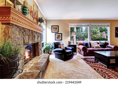 Luxury Family Room With Cozy Stone Trimmed Fireplace. Rich Leather Couch And Armchair Create Comfort Atmosphere