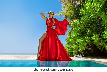 Luxury fashion. Elegant fashion model. Stylish female model in red long gown dress on the Maldives beach. Elegance. Classy woman in amazing red dress near the pool. Couture. Vogue.