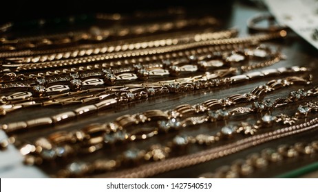 Luxury Gold Jewelry Chains, Bracelets Background, Selective Focus. Stylish Beautiful Bijouterie Hanging On The Stand In The Accessories Store. Various Jewelry Bijouterie.