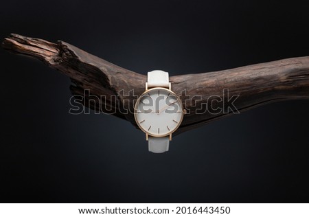 A luxury gold watch with a black dial. A watch on a beautiful stand, on a beautiful lightly lit gray background. Woman Man fashion. watch with white dial and white strap
