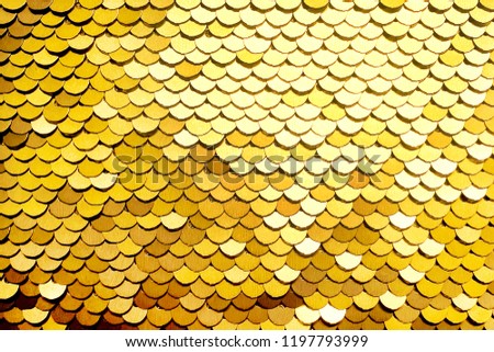 Luxury golden Background. Abstract Texture scales with gold Sequins close-up. Glamor Background with shiny Sequins on fabric, macro. Abstract background with gold sequins color on the fabric.