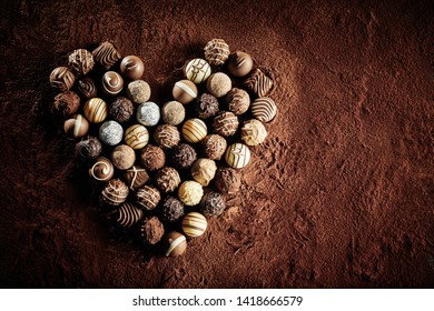 Luxury handmade chocolate pralines in a heart shape symbolic of romance and love on a background of cacao powder with copy space for valentines