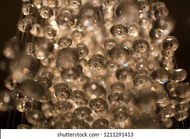 Luxury High End Design. Crystals On Strings Grouped Together With Nice Lighting. Shiny Lights Black Background. Abstract Bokeh. Luxury Decorative Background.