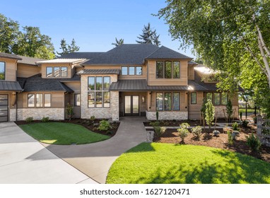 Luxury Home Exterior On Sunny Day With Blue Sky. Features Three Car Garage, Large Driveway, And Elegant Design