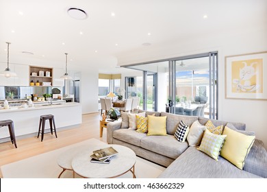 Luxury House Interior Focusing The Living Room Sofa And Pillows  Next Round Table On The Carpet Beside The Kitchen And The Glass Door Entrance To Outside