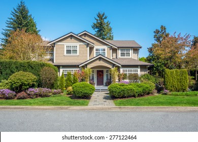 Luxury house with nicely trimmed front yard, lawn in a residential neighborhood. Home exterior.