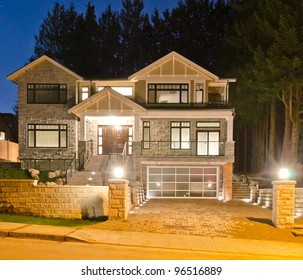 A Luxury House With The Original Glass Garage Doors In Suburbs At Dusk In Vancouver, Canada