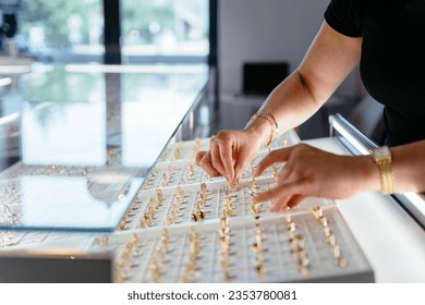 Luxury jewelry store business concept. Side view of woman an as salesperson behind counter in jewelry store. Holds ring.