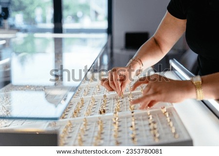 Luxury jewelry store business concept. Side view of woman an as salesperson behind counter in jewelry store. Holds ring.