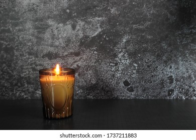 The Luxury Lighting Aromatic Scent Amber Color Glass Candle Display In The Minimal Design Bed Room With Black Concrete Background