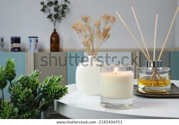 luxury lighting aromatic scented candle is on white\
metal table with ceramic vase and reed diffuser to creat relax\
ambient in the bedroom with background of nice bedroom and curtain\
on Valentine day