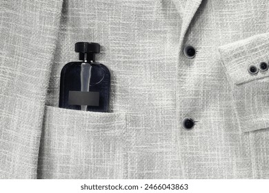 Luxury men's perfume in pocket of grey jacket, top view. Space for text