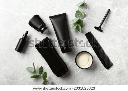 Luxury men's skincare beauty products set on stone desk table. Flat lay black shampoo bottle, jar of moisturizer cream, deodorant, razor, serum.