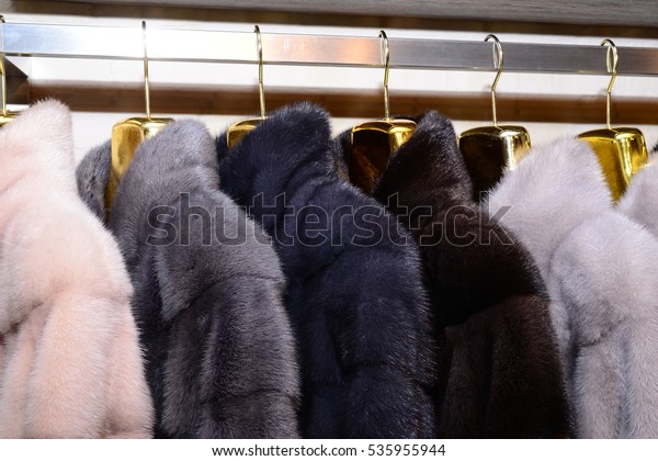 Luxury mink coats. Pink, grey, dark grey, pearl color\
fur coats on showcase of market. Best gift for a woman. Outerwear.\
Close up.