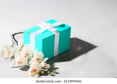 Luxury Mint Green Gift Box With Silk Ribbon On White Background With  White Orchid Sflower.Copy Space