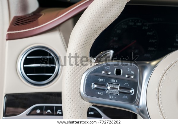 Luxury Modern car\
interior with white leather steering wheel with media phone control\
buttons, navigation screen multimedia system background. Modern car\
interior details