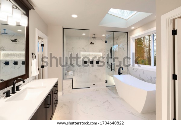 Luxury modern home bathroom interior with dark\
brown cabinets, white marble, walk in shower, free standing tub,\
two mirrors, flowers.