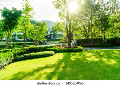 Luxury Modern House With A Beautiful Landscaped Front Yard With Fresh Green Grass Both Shrub And Trees Garden Landscape Design Grass Smooth Lawn With Curve Form The Bush Mountain Blue Sky Background.