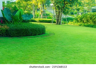 Luxury Modern House With A Beautiful Landscaped Front Yard With Fresh Green Grass Both Shrub And Trees Garden Landscape Design Grass Smooth Lawn With Curve Form The Bush Mountain Blue Sky Background.