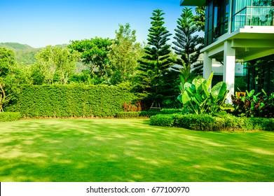 Luxury Modern House With A Beautiful Landscaped Front Yard With Fresh Green Grass Both Shrub And Flower Garden Landscape Design Grass Smooth Lawn With Curve Form The Bush Mountain Blue Sky Background,