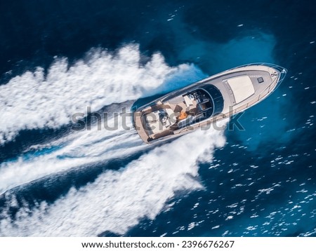 Luxury motor boat cruising on turquoise Mediterranean water, aerial drone view.