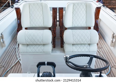 Luxury motorboat control cabin with white leather seats, steering wheel and gear lever.