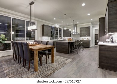 Luxury New Construction Home With Open Floor Plan: Dining And Kitchen Design. Rustic Wood Dining Table Matches With Modern Style Leather Chairs. Kitchen Accented With Dark Cabinetry. Northwest, USA