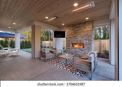 Luxury Outdoor Relaxing Living Room With Large Stone Fireplace, TV, Rug And Beige Sofa. 