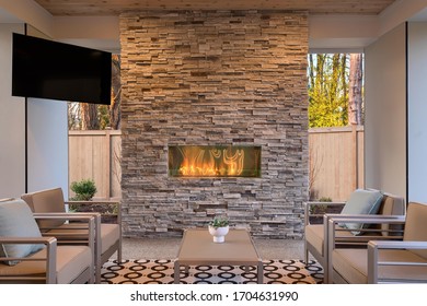 Luxury Outdoor Relaxing Living Room With Large Stone Fireplace, TV, Rug And Beige Sofa. 