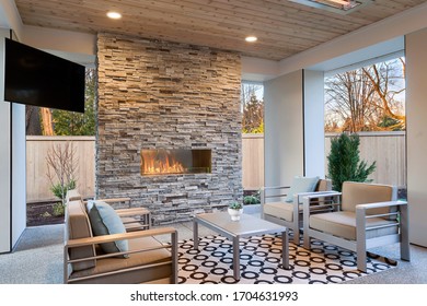 Luxury Outdoor Relaxing Living Room With Large Stone Fireplace, TV, Rug And Beige Sofa. 