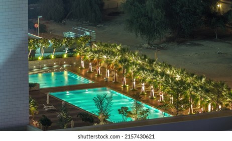 Luxury Outdoor Swimming Pool And Relaxing Zone Around Aerial Timelapse With Night Illumination. Top View With Palms In Downtown, Dubai