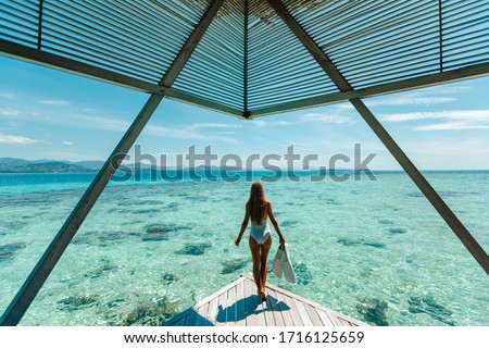 Luxury overwater bungalows Maldives resort woman going snorkeling from private hotel room island.  Travel vacation.  Aqua menthe trendy color of the new year 2020