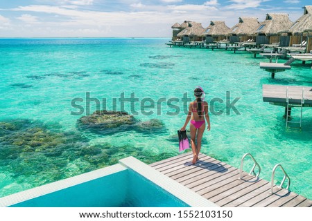 Luxury overwater bungalows Tahiti resort woman going snorkeling from private hotel room on Bora Bora island, French Polynesia. Travel vacation recreational activity watersport fun leisure.