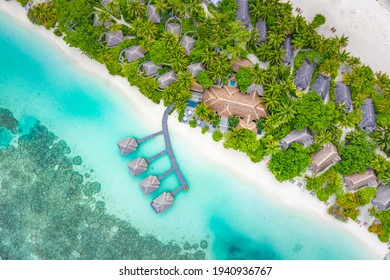 Luxury overwater villas with coconut palm trees, blue lagoon, white sandy beach at Maldives islands. Top view, summer vacation, holiday landscape. Amazing relaxing nature aerial scene, traveling scene - Powered by Shutterstock