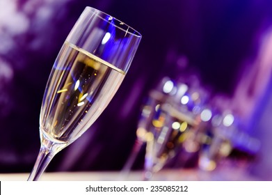 Luxury Party Champagne Glass In Nightclub Neon Lilac, Blue And Purple Lights. Blurry Closeup.