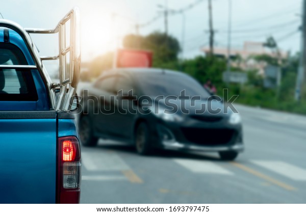 Luxury of\
pickup blue car stop on the junction road. Traveling in the\
provinces during the bright period. Open light brake. Blurred\
images of cars passing through the\
front.