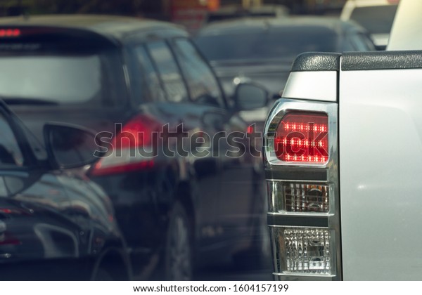 Luxury of pickup silver\
car stop on the junction by traffic light control in across.\
Traveling in the provinces during the bright period. Open light\
brake. with many cars.
