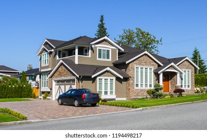 Luxury Residential House With Green Hedge On Side And Green Lawn In Front. Suburban Family House With Double Garage And Car Parked On Paved Driveway