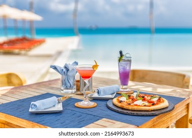 Luxury resort hotel poolside, outdoor restaurant on the beach, ocean and sky, tropical island cafe, tables, food. Summer vacation or holiday, family travel. Palm trees, infinity pool, cocktails, relax - Powered by Shutterstock