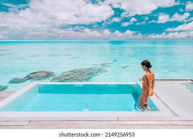 Luxury Resort Travel Vacation Destination Idyllic Overwater Bungalow Villa Woman Relaxing By Infinity Pool. Social Media Influencer Traveler Luxurious High End Lifestyle.