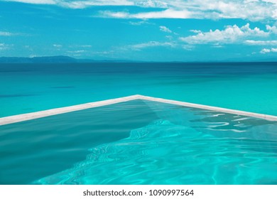 Luxury resort villa with infinity pool over blue seashore. Summer vacations, idyllic scene. Beautiful destination travel tour background. 