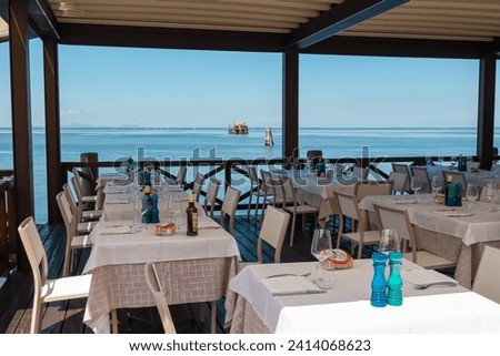 Luxury restaurant on island of Pellestrina with panoramic view of Venetian Lagoon in Venice, Venetian Lagoon, Veneto, Italy. Laid table in tranquil atmosphere in summer at seaside. Going out vacation Foto stock © 