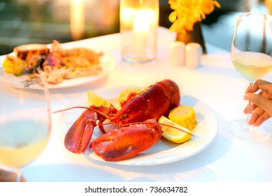 Luxury Romantic Candle Light Dinner Setup By The Pool With Plate Of Lobster And Seafood BBQ