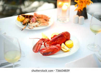 Luxury Romantic Candle Light Dinner Setup By The Pool With Plate Of Lobster And Seafood BBQ